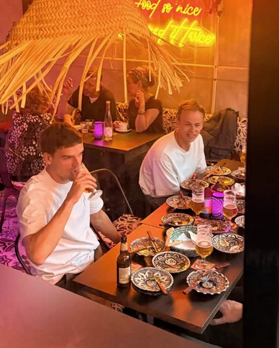 Vrienden delen schalen en drinken een biertje aan tafel bij LaSqala in Zwolle
